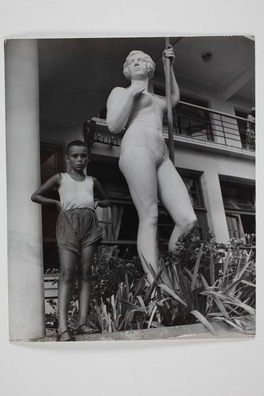 Fiú egy a szanatóriumban álló robosztus női alak szobra mellett. A Fekete-tenger mellett, Batum, Grúzia, USSR, 1947. Fényképezte Robert Capa. Magyar Nemzeti Múzeum gyűjteménye, Budapest 